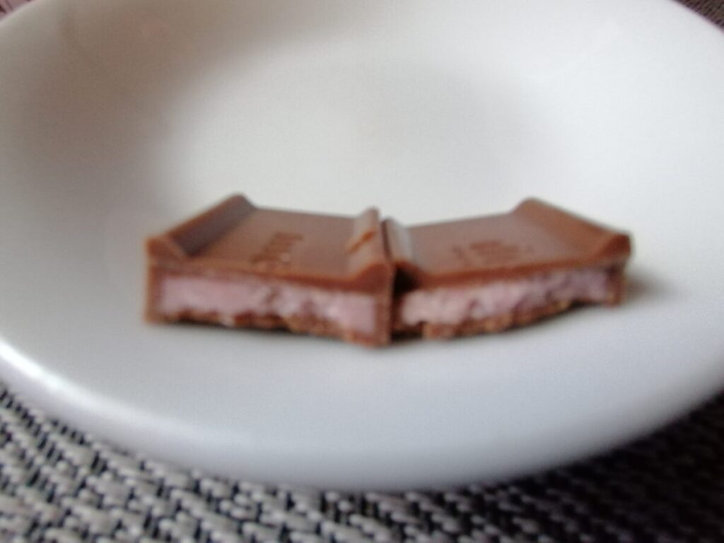 半分に割った明治ストロベリーチョコレートの断面。中のピンク色のイチゴチョコが見える。