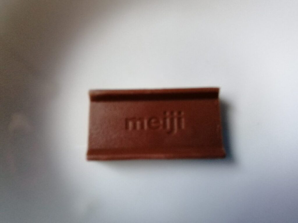 個包装から出した明治ストロベリーチョコレート。表面にmeijiの刻印がある。